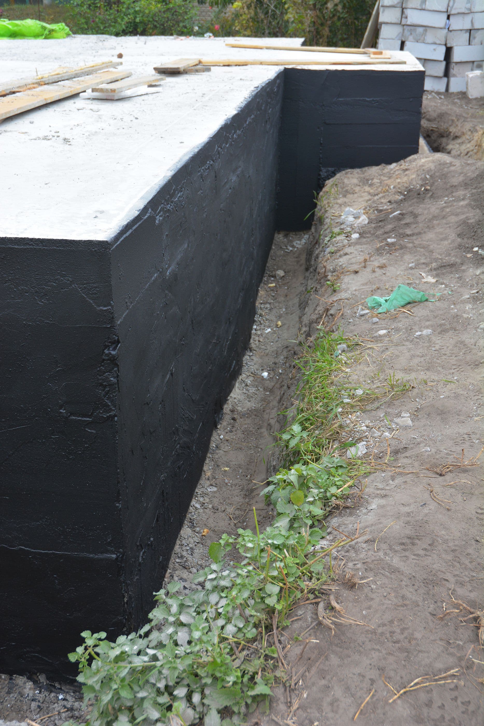 Exterior foundation wall coated with a waterproof membrane to help prevent water intrusion and protect the foundation from long-term moisture damage.