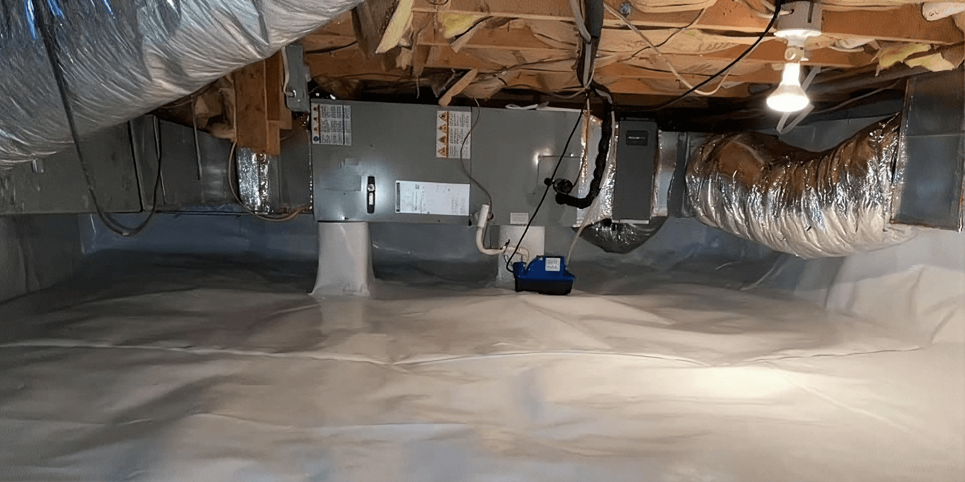 Fully encapsulated crawlspace with a sealed white vapor barrier surrounding HVAC equipment and ductwork to help protect against moisture and improve indoor air quality.