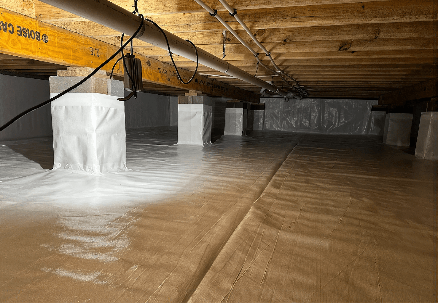 Clean, fully encapsulated crawlspace with a sealed white vapor barrier covering the floor, foundation walls, and support piers to protect against moisture and improve indoor air quality.